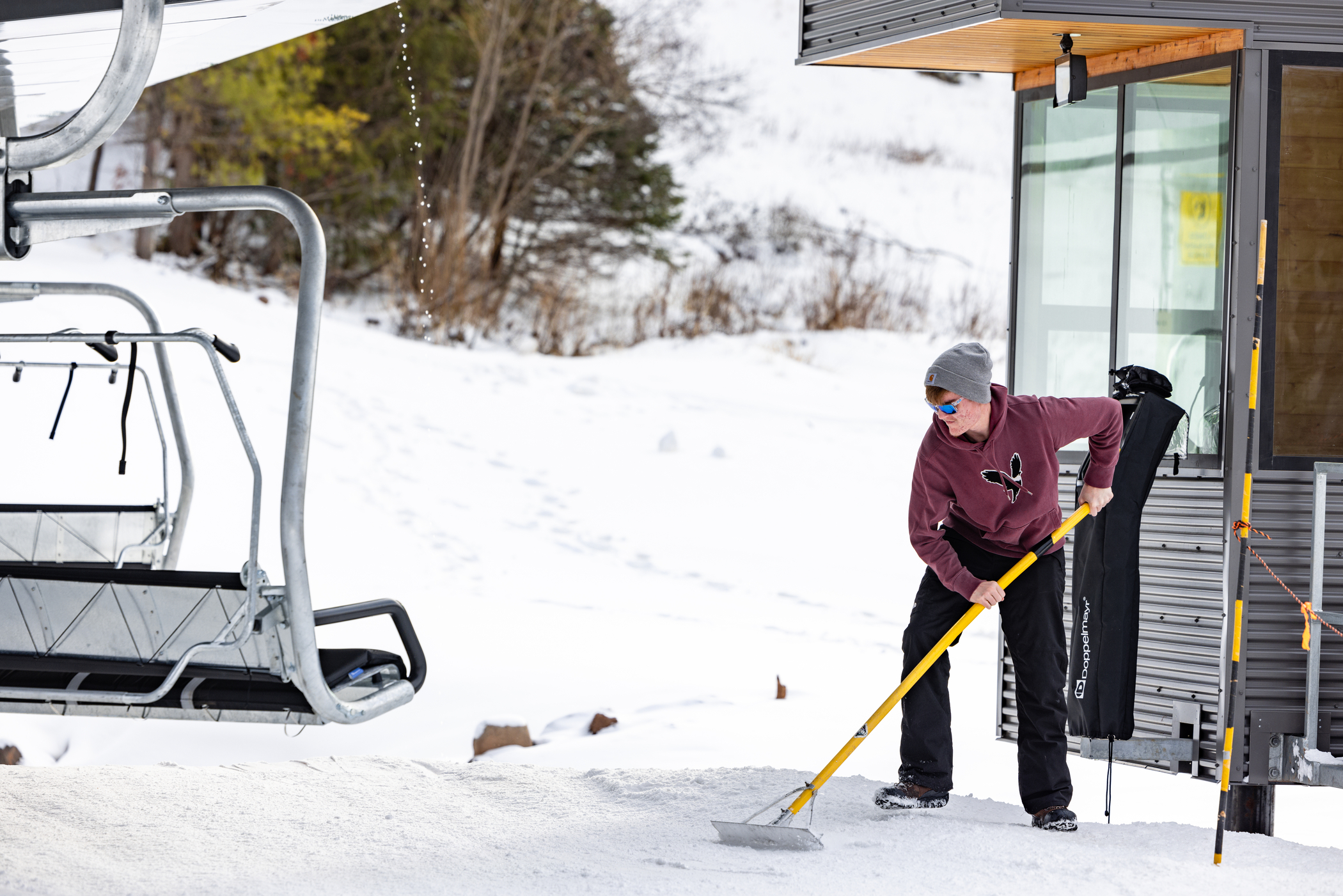 Lift operator rakes a loading ramp for skiers and riders.