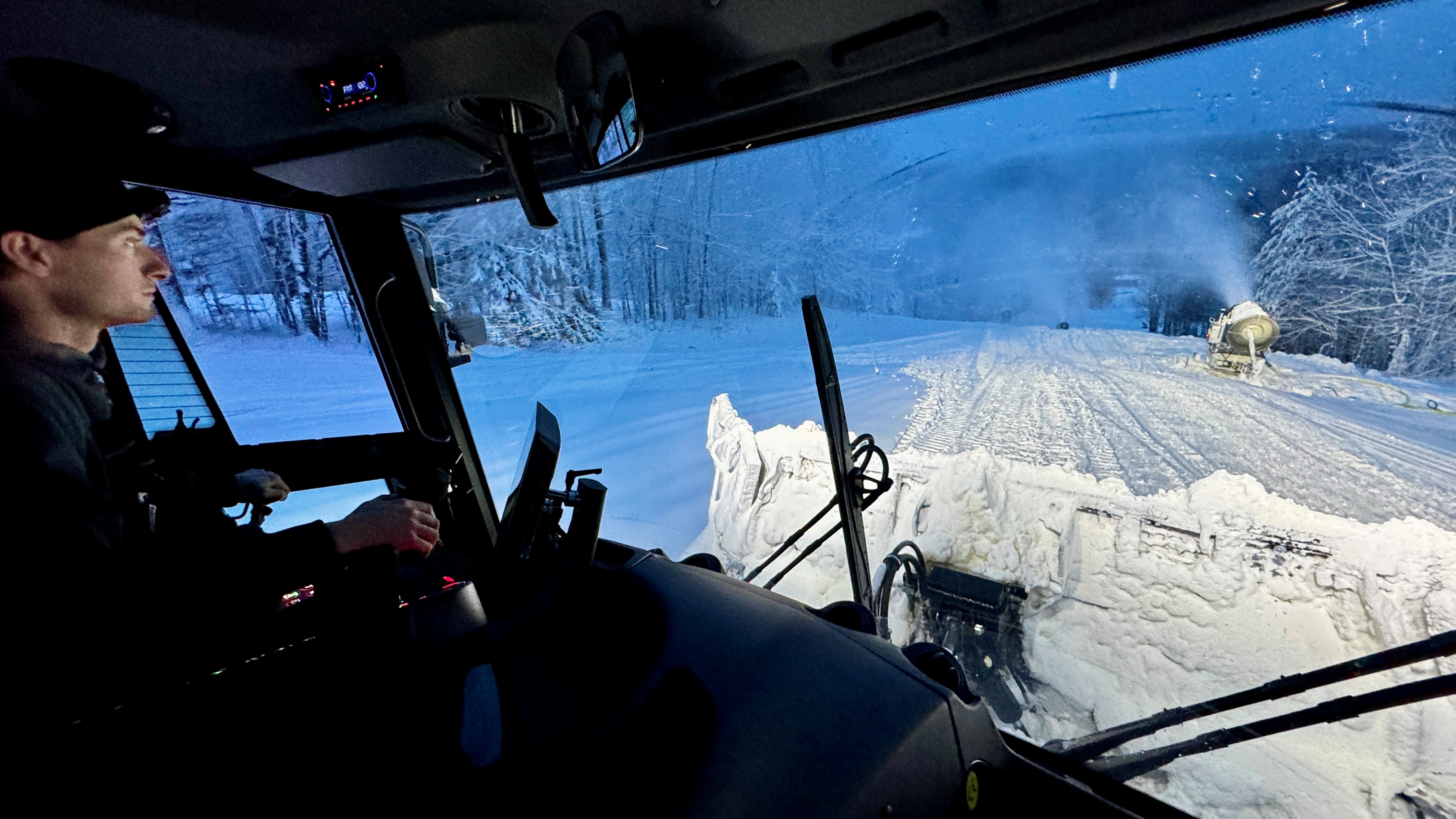 View out the windshield of a snow grooming machine.