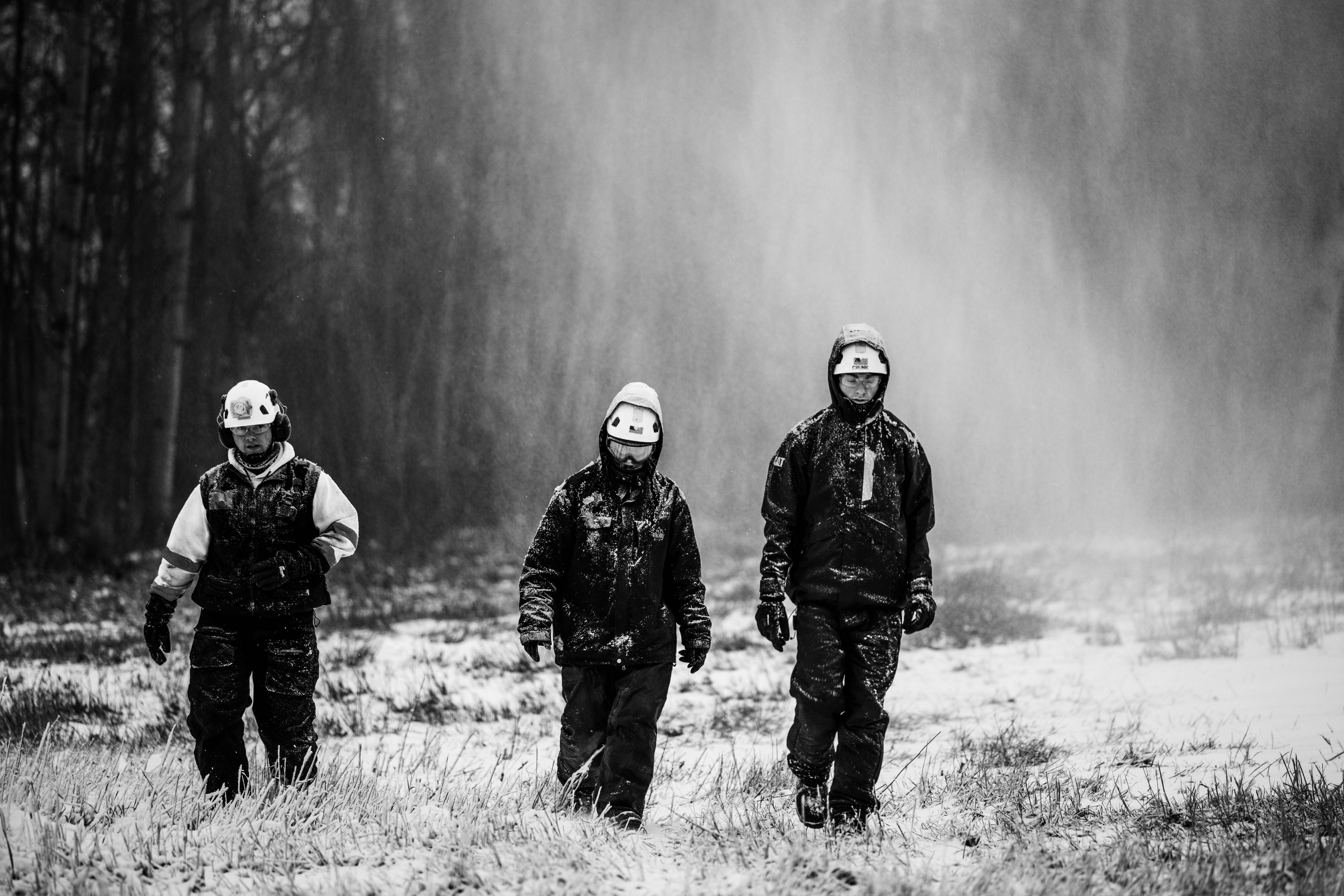 Black and white photo of snowmakers walking through a plume.