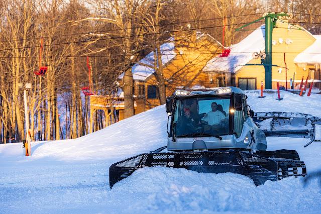 snowcat pushing pile of snow