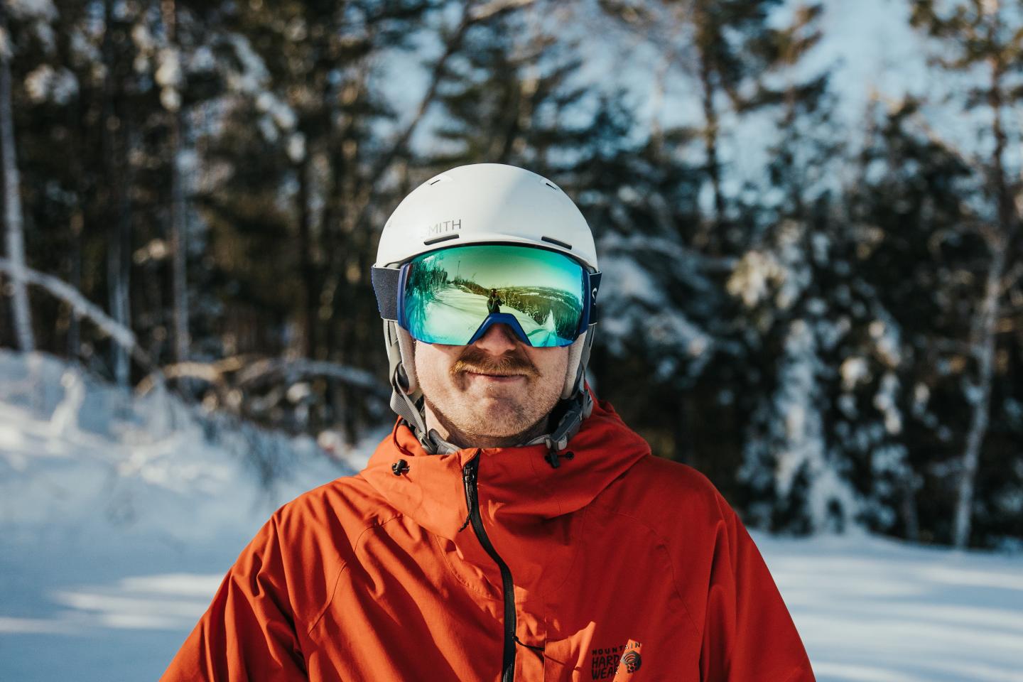 Male skier posing in helmet and reflective ski goggles.
