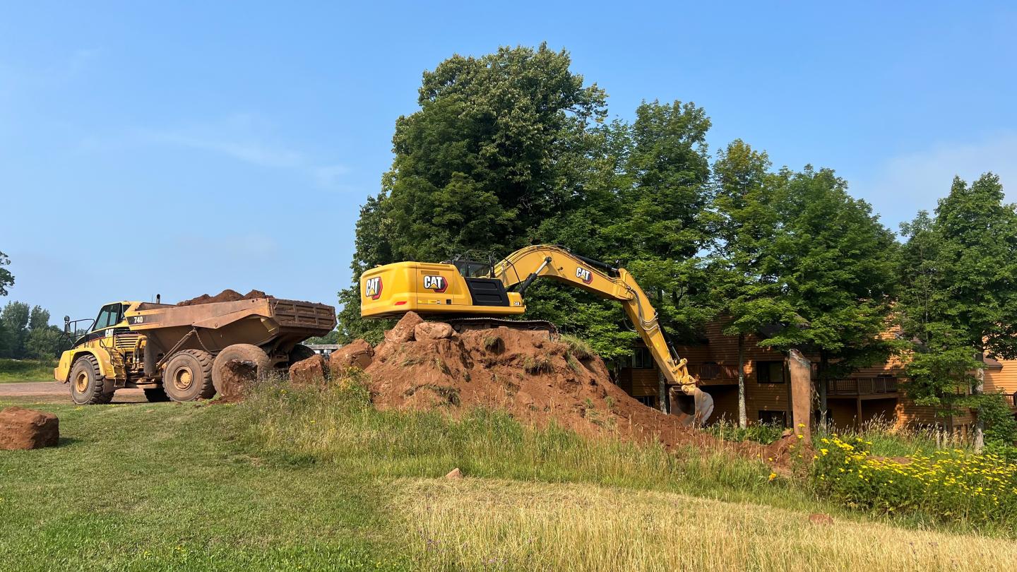 Excavator loads material into an off-road dump truck.