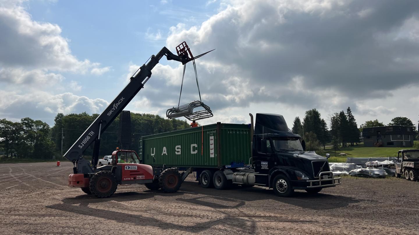 Ski lift chairs being unloaded with a rough-terrain forklift. 