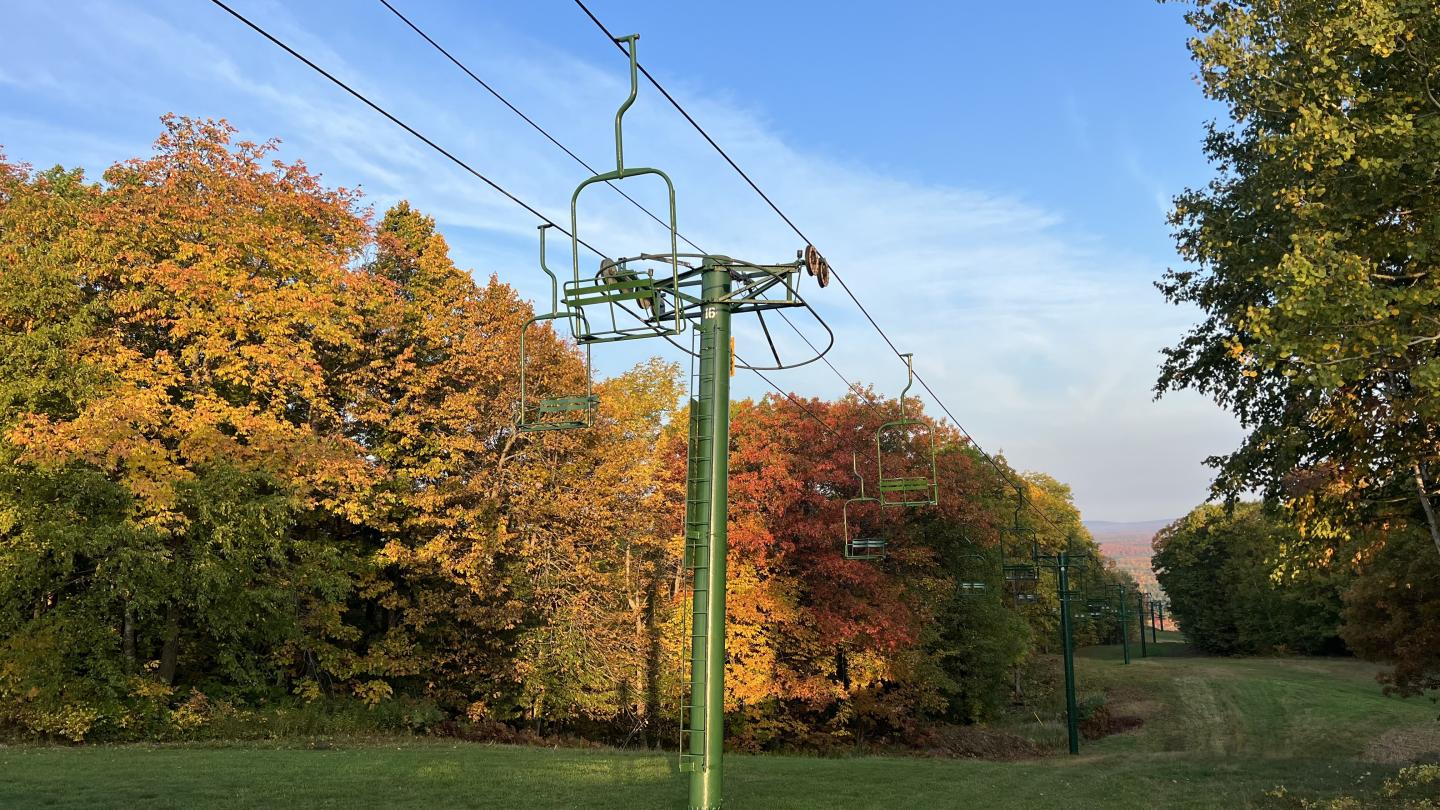 Freshly painted chairlift with fall foliage in the background.
