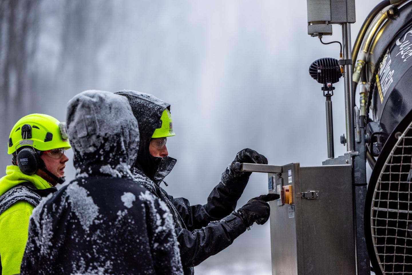 Employees adjust settings on a snowgun.