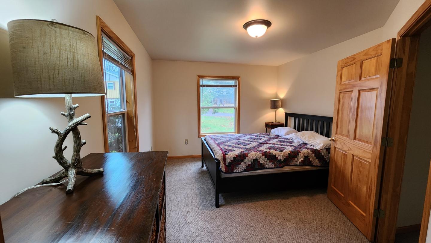 Cozy bedroom with wood furniture, quilted bed, and window view.