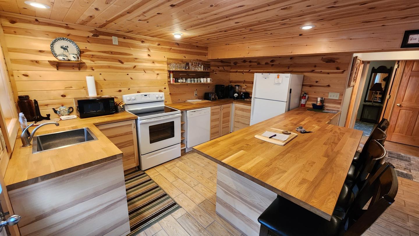 Cozy wooden kitchen with a stove, fridge, and island counter.