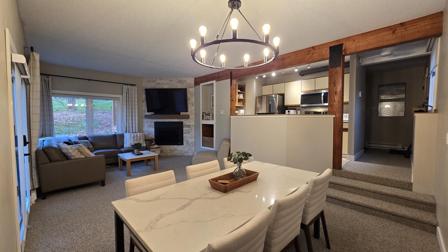 Modern living and dining room with neutral colors and large windows.