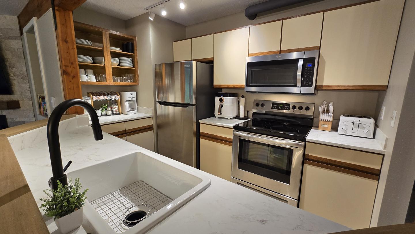 Modern kitchen with stainless steel appliances and light wood cabinets.