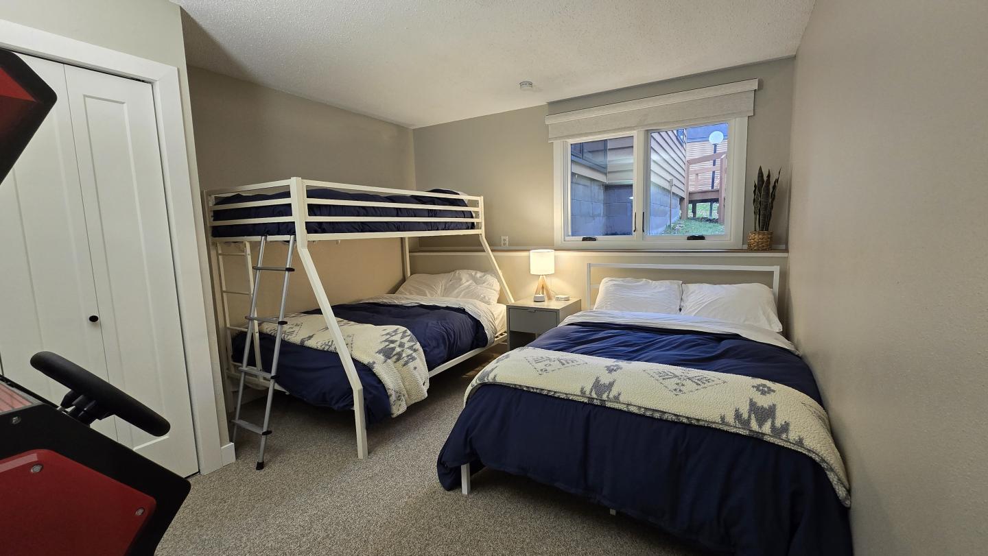 Cozy bedroom with bunk bed, single bed, and soft lighting.
