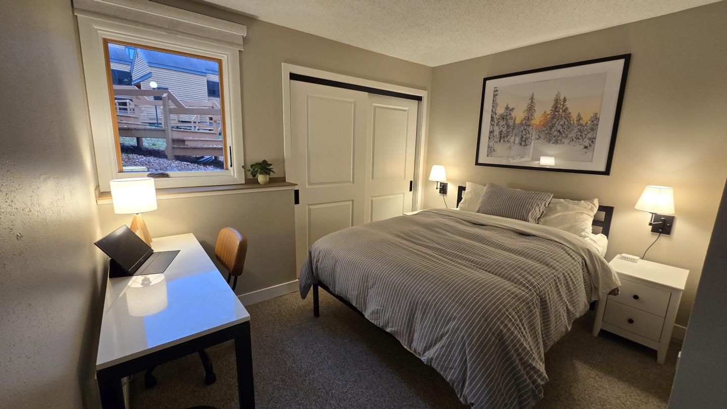 Cozy bedroom with a bed, desk, and warm lighting.