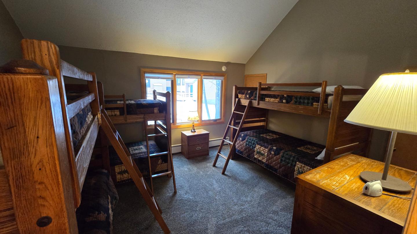 Cozy room with wooden bunk beds, a nightstand, and warm lighting.