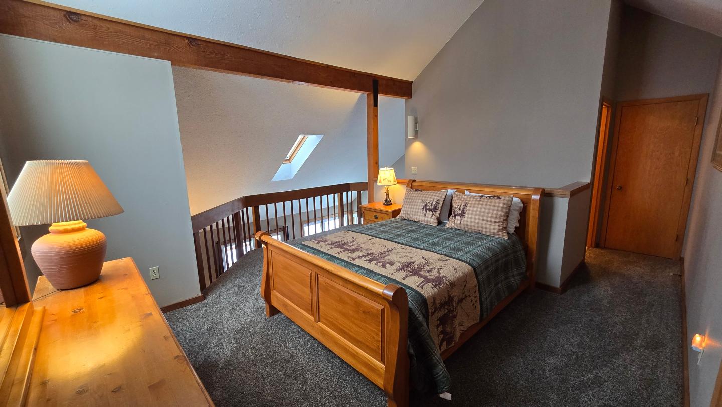 Cozy attic bedroom with wooden bed and warm lighting.