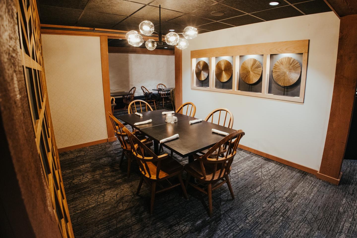 Dining room with a wooden table, chairs, modern chandelier, and abstract wall art.