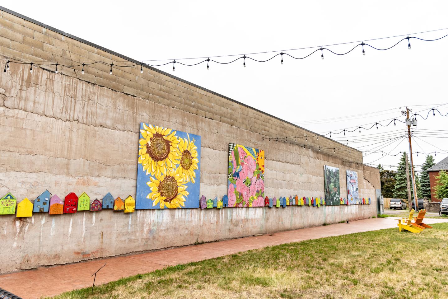 Colorful murals and birdhouses on a concrete wall, outdoor setting.