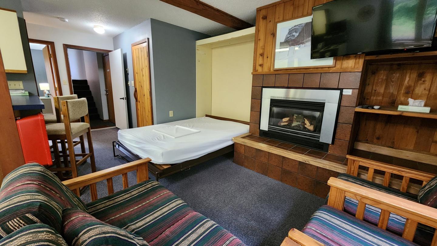 Cozy living room with fireplace, pull-out bed, and striped couches.