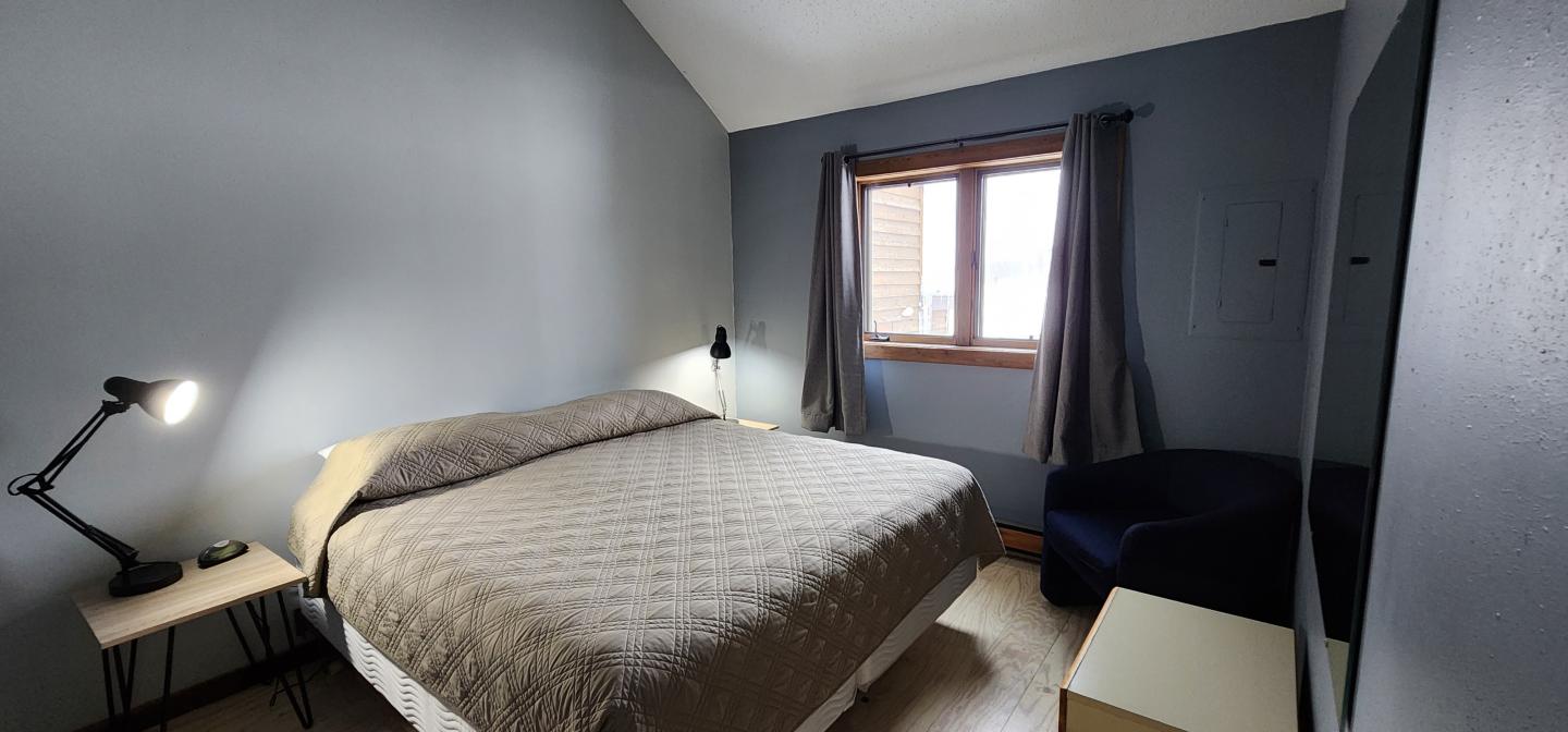 Cozy bedroom with a large bed, side tables, lamps, and a window with curtains.