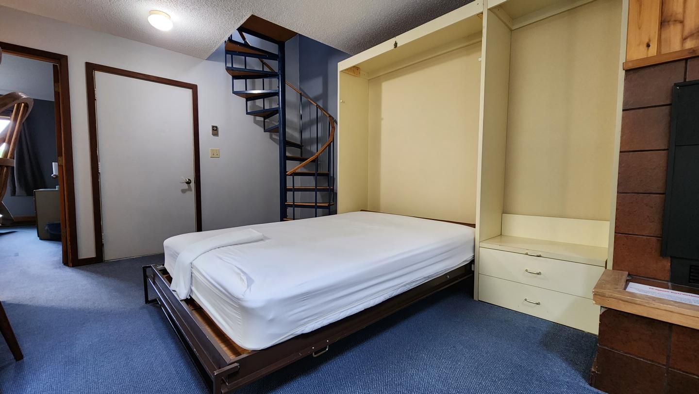 Murphy bed folded out in a room with a spiral staircase.