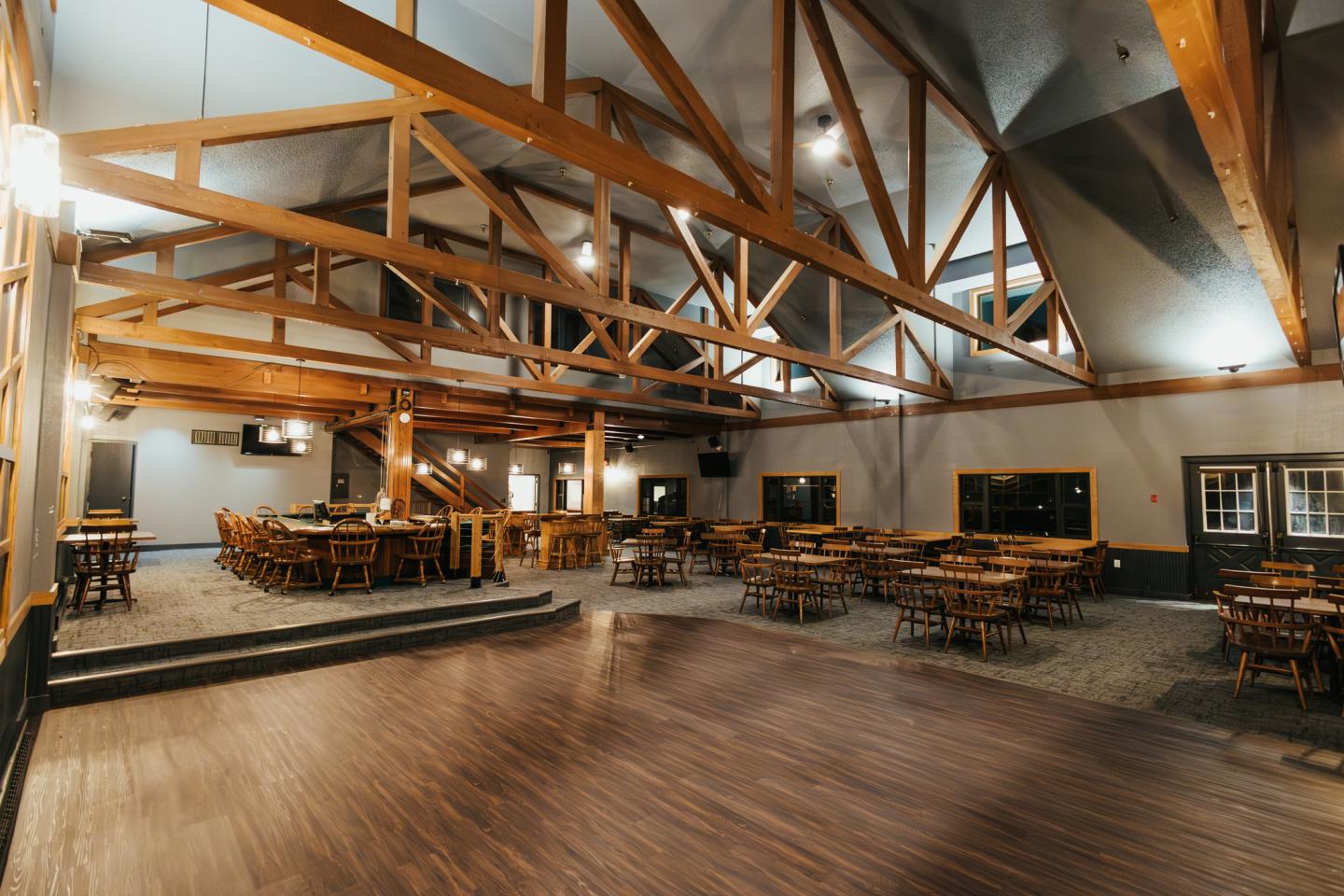 Spacious restaurant interior with wood beams and empty tables.