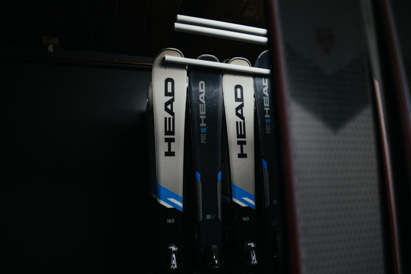 Skis with black, white, and blue design stored in a rack.