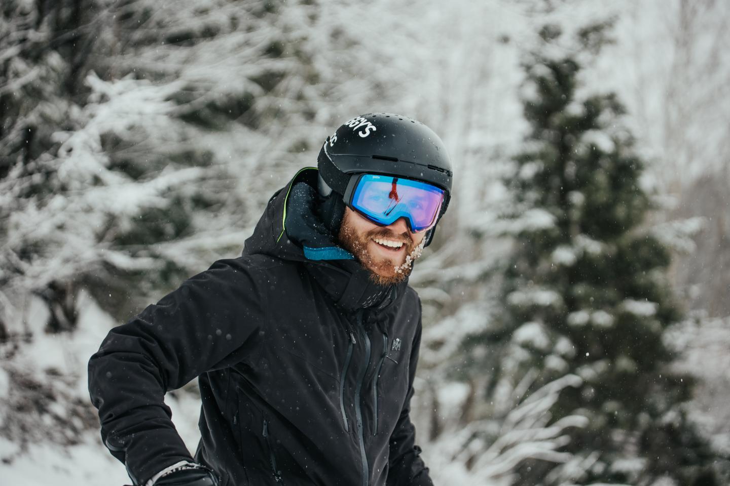 Smiling person in ski gear on a snowy mountain.