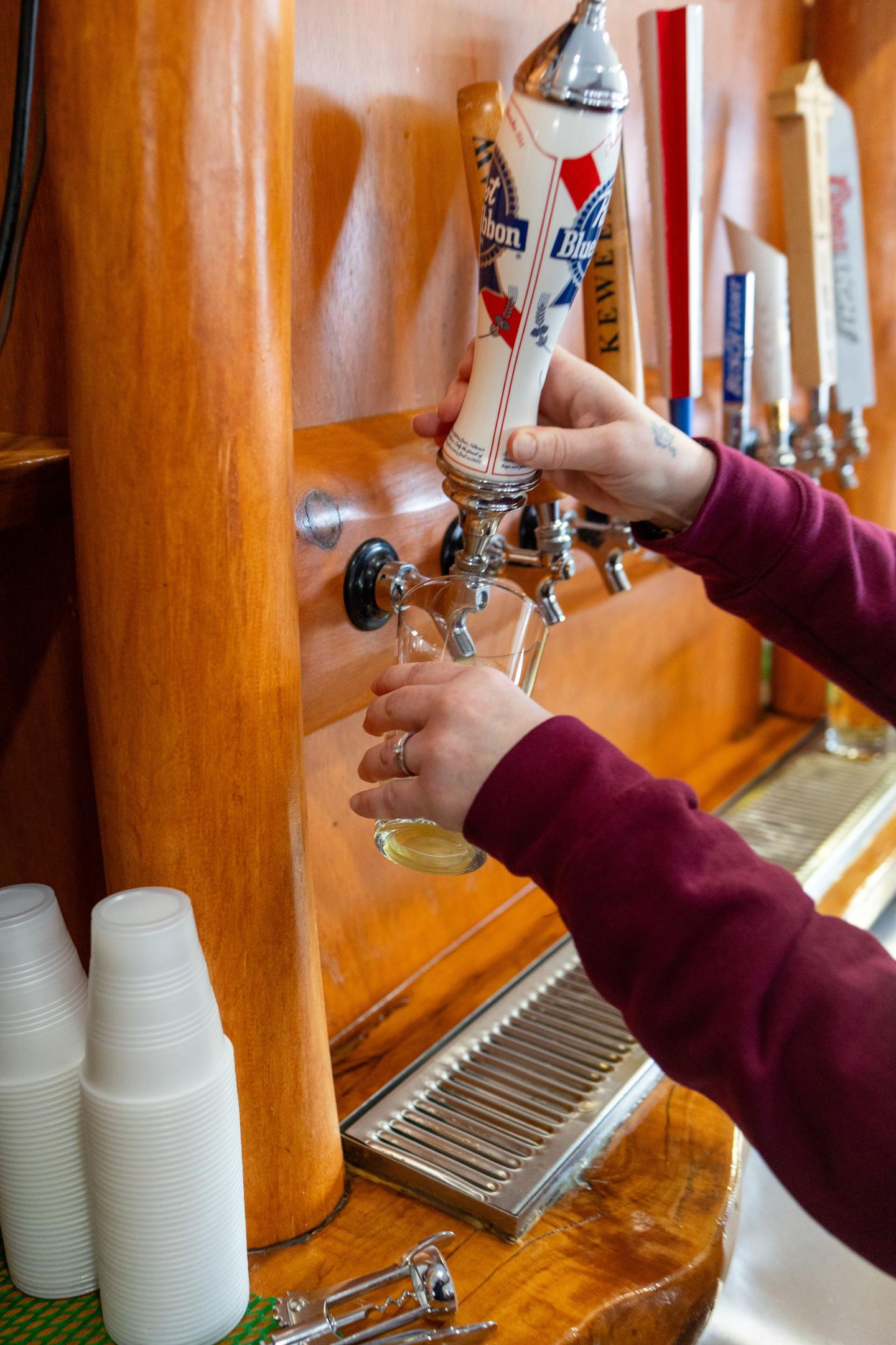 Beer being poured from tap into a glass at a bar.