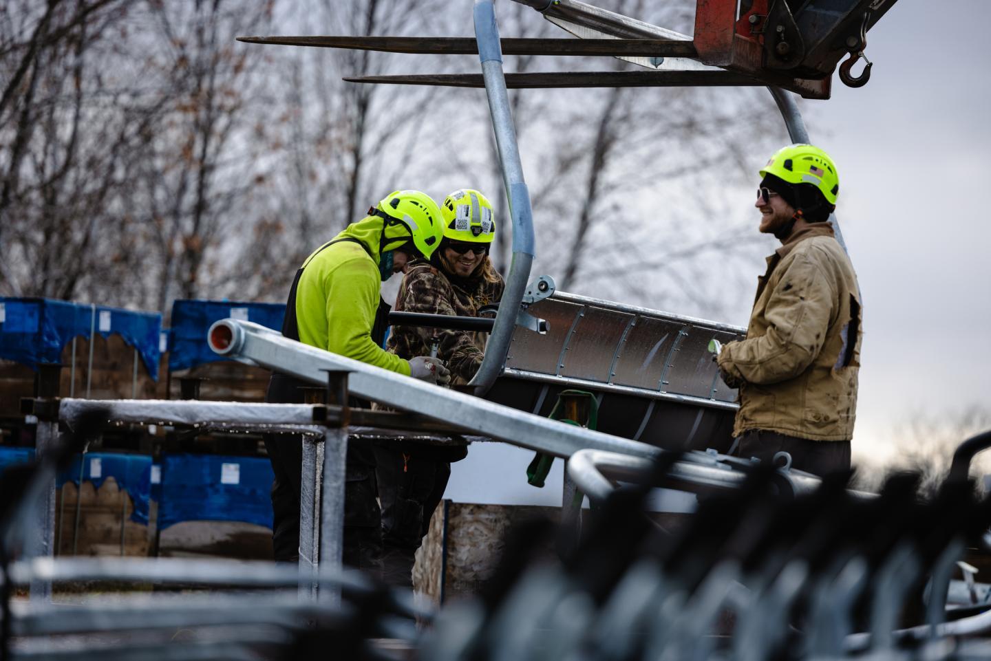 Workers in helmets assembling metal beams on a construction site.