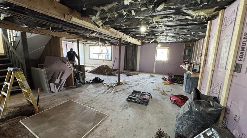 Room under renovation with exposed beams and scattered construction materials.