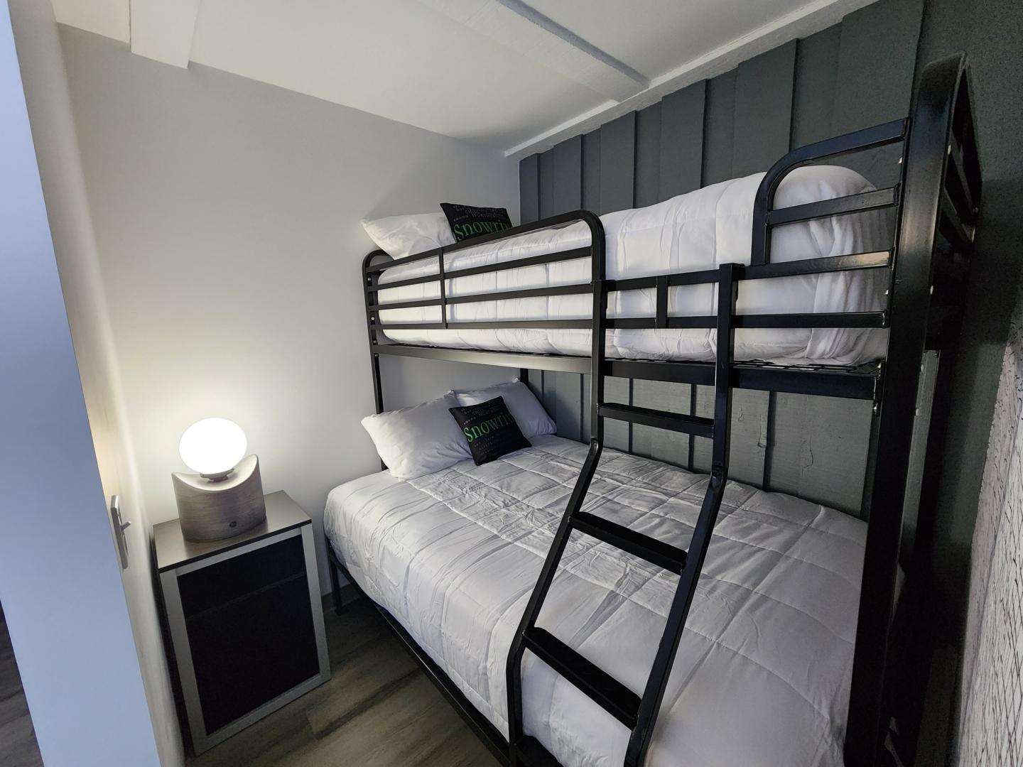 Bunk bed in a small room with a glowing round lamp on a side table.