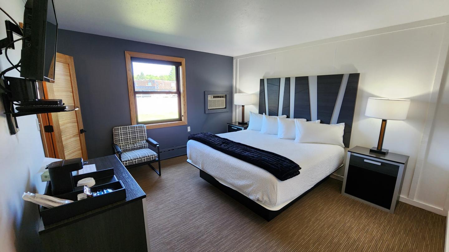 Hotel room with a king-size bed, blue accent wall, and modern furnishings.