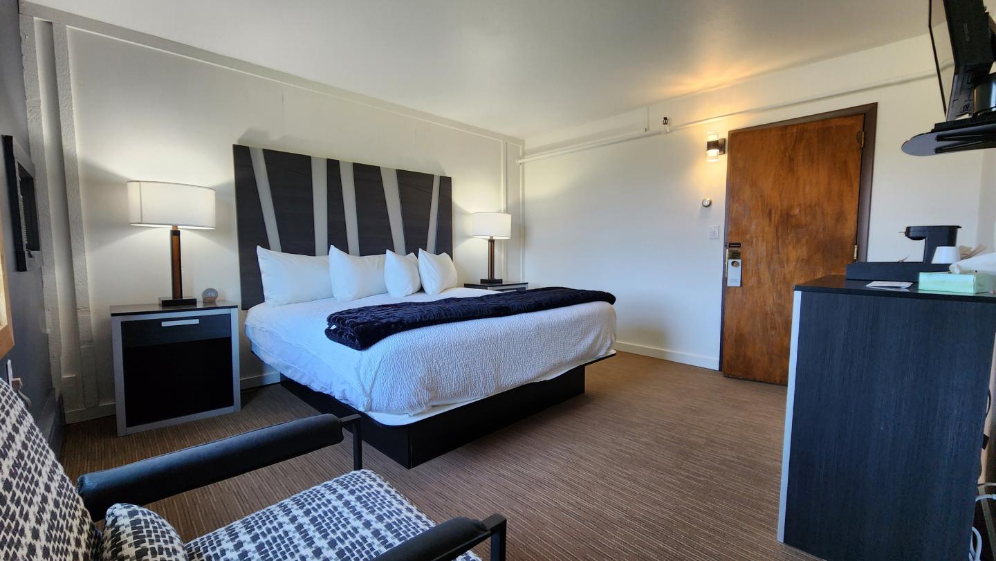 Cozy hotel room with a large bed, wooden door, and modern decor.