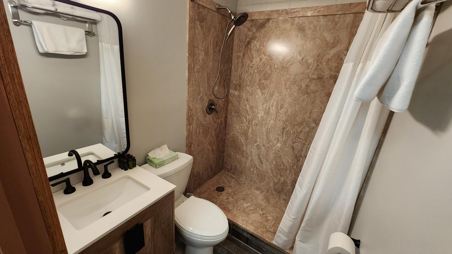 Compact bathroom with a marble shower, sink, and toilet.