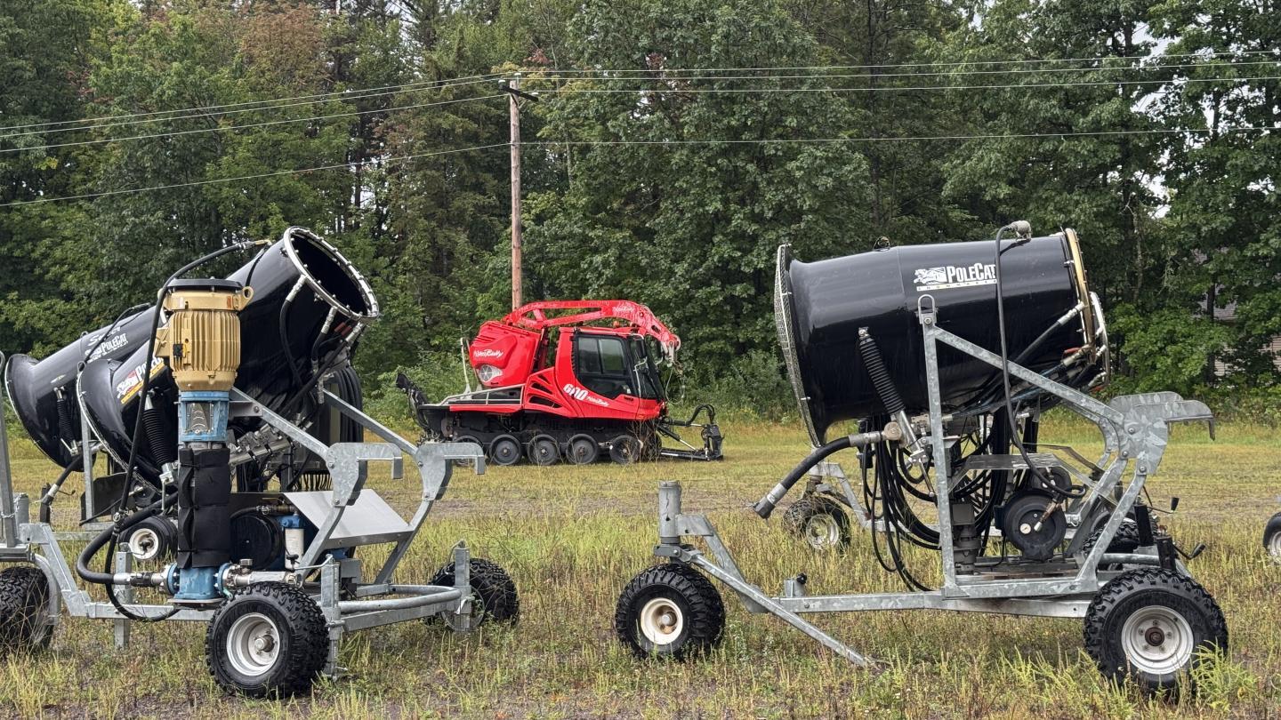 Snow machines on a field with trees in the background.