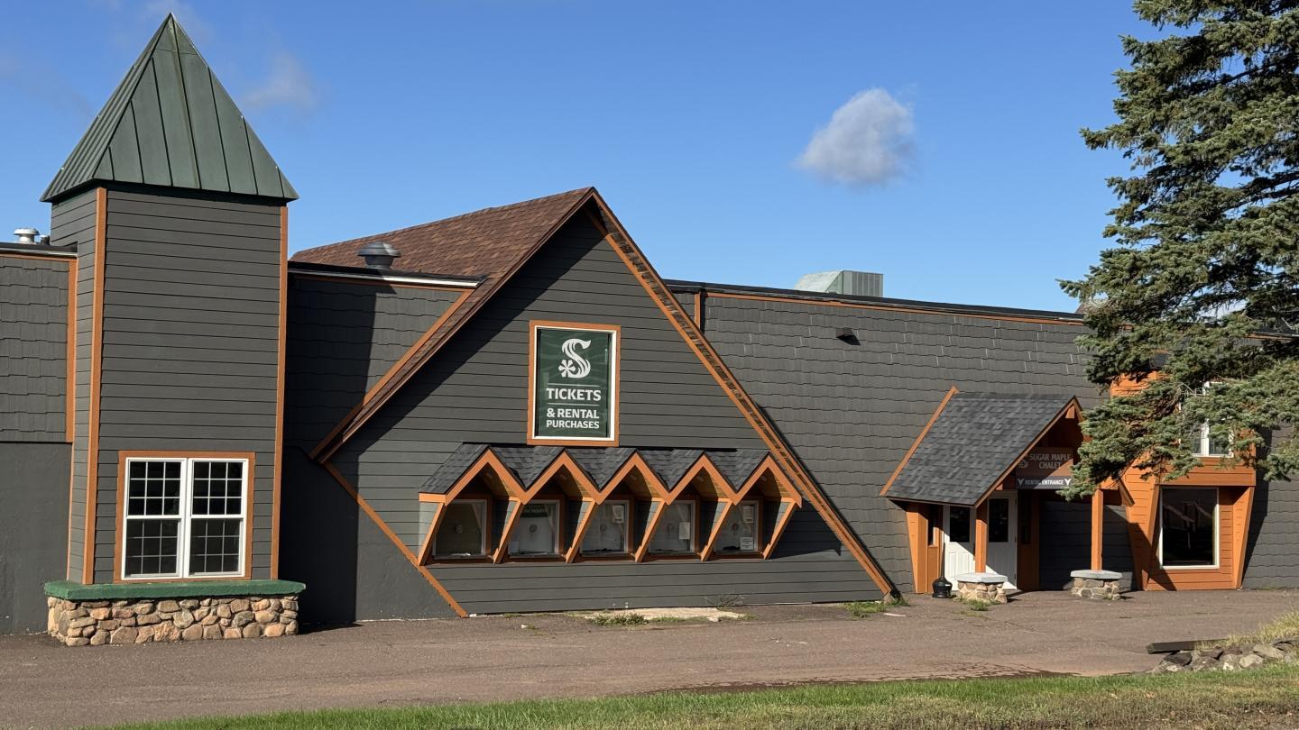 Building with geometric windows and a tower, set against a blue sky.