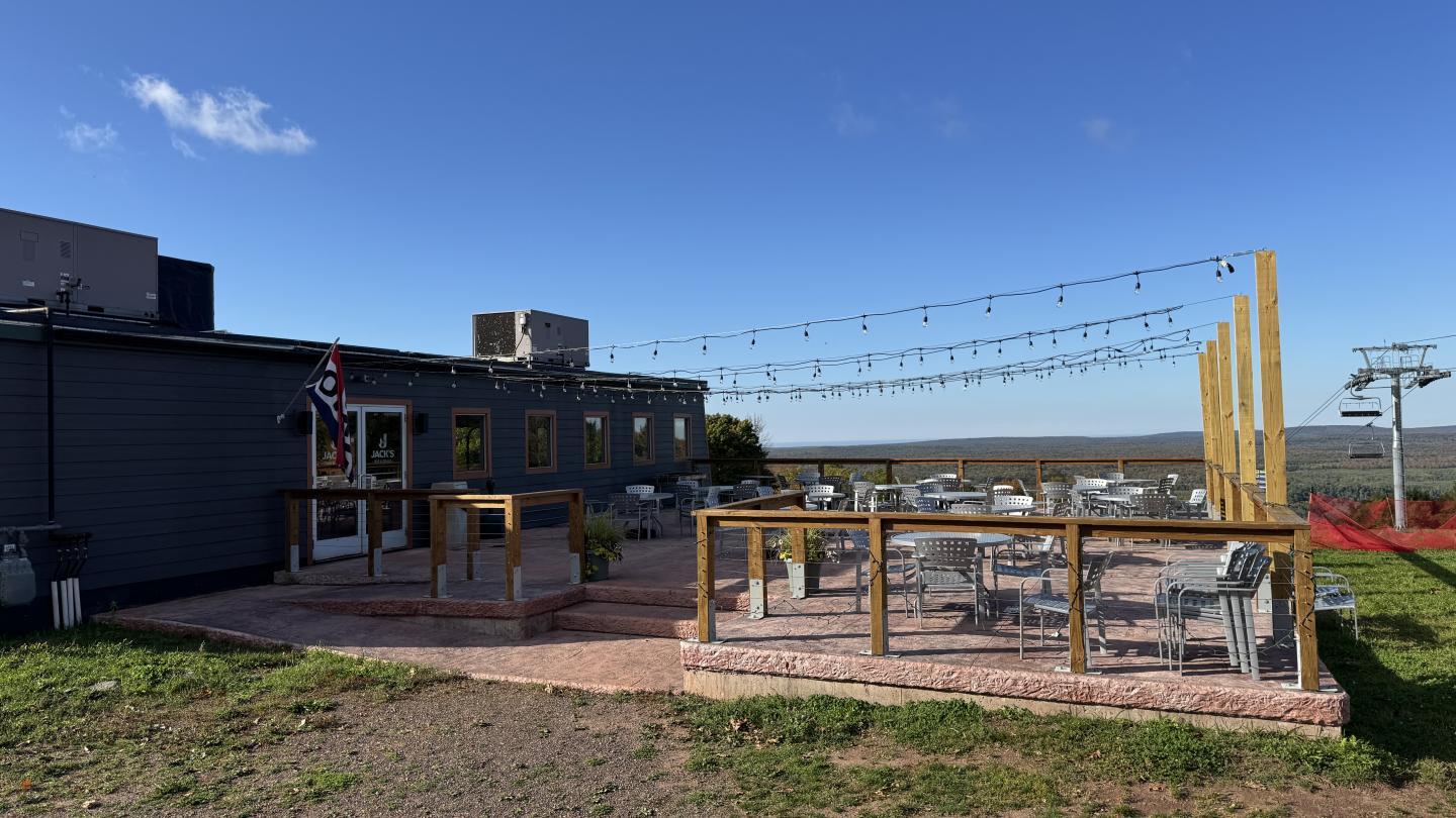 Outdoor patio with tables, string lights, and clear sky.