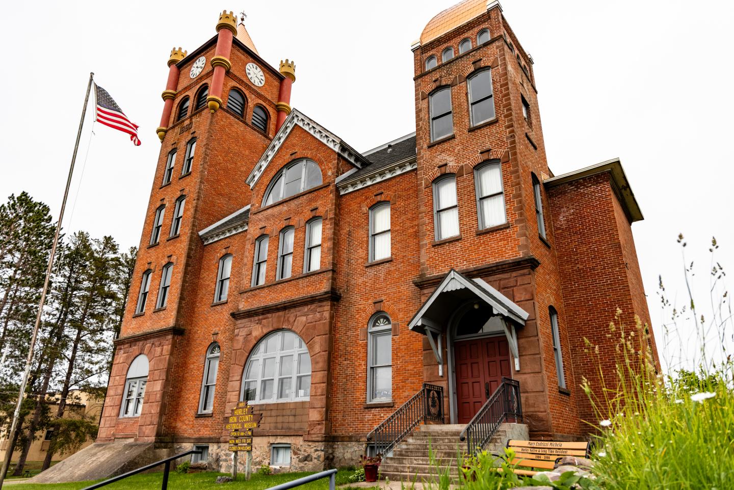 Historic red brick building with tall clock tower and American flag.