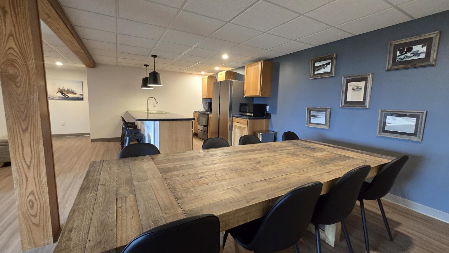 Dining area with a large wooden table, black chairs, and blue accent wall.