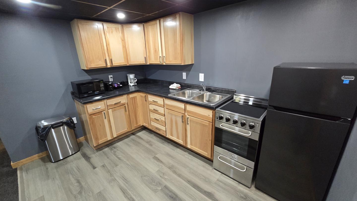Cozy kitchen with wooden cabinets, black appliances, and gray walls.