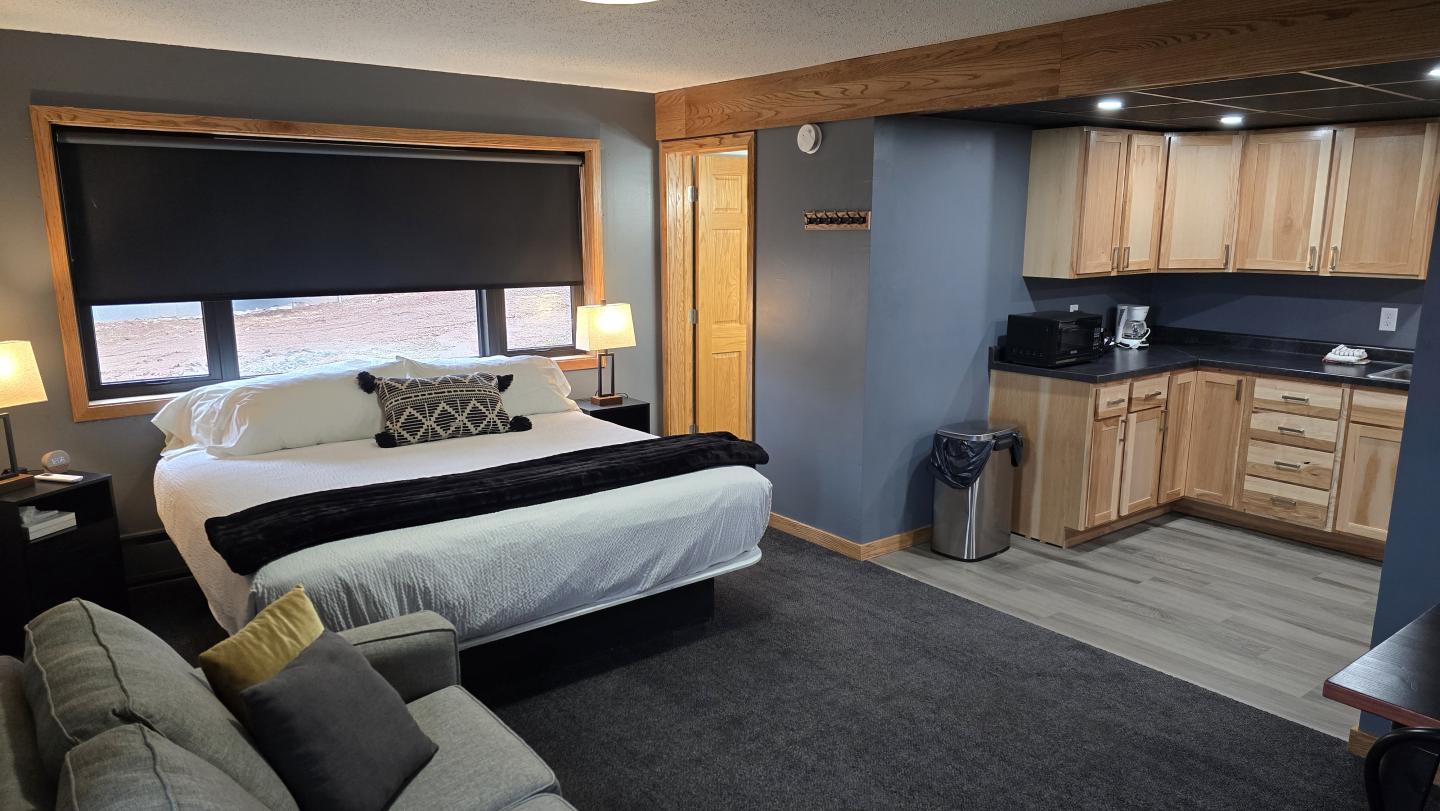 Cozy hotel room with bed, sofa, and kitchenette.