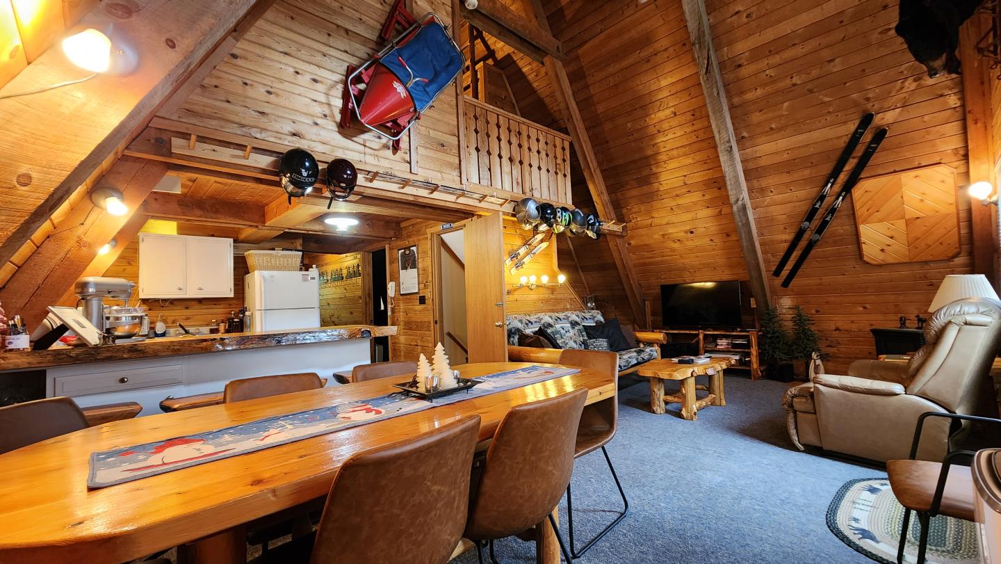 A-frame cabin interior with wooden walls, dining table, and cozy seating area.