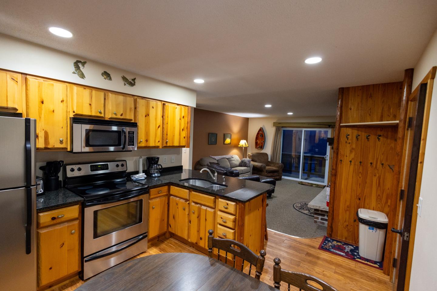 Cozy wooden kitchen and living area with modern appliances and warm lighting.