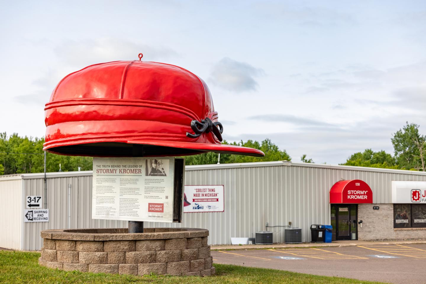 Giant red hat sculpture outside a building with a similar red awning.