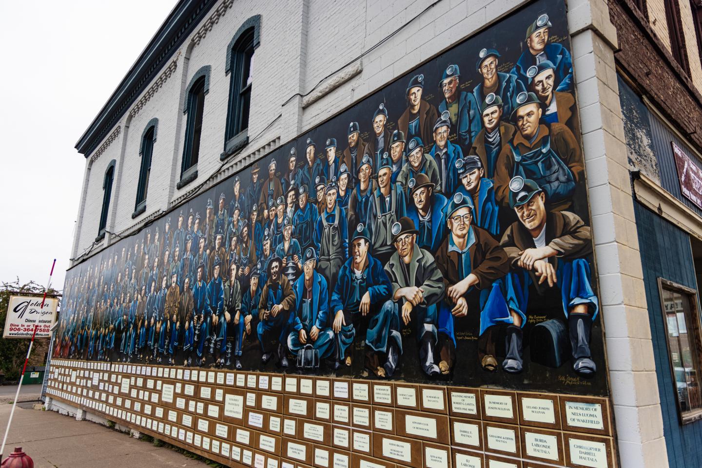 Mural of miners in blue overalls on a large building wall.