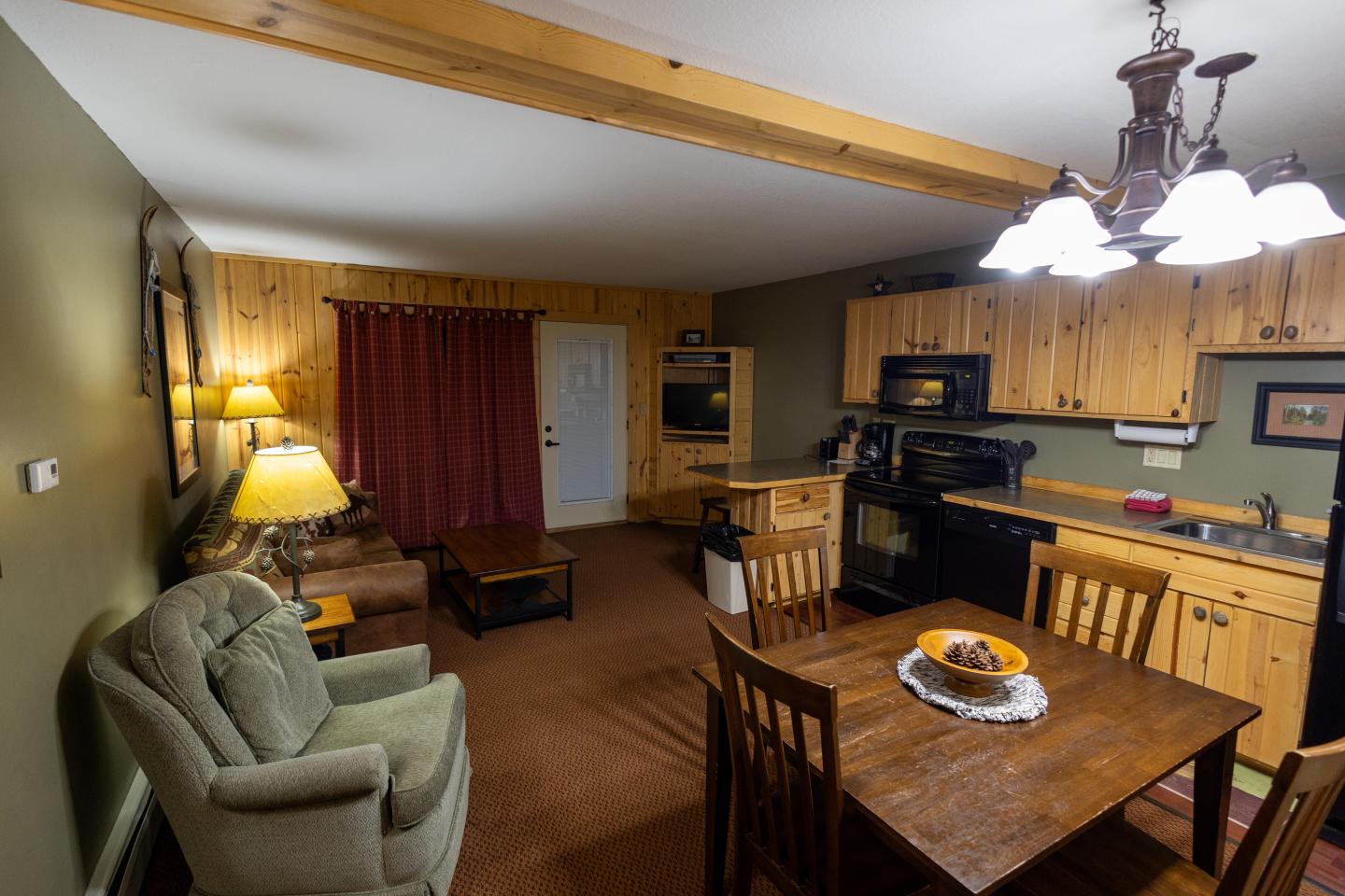 Cozy living room and open kitchen with wood accents and warm lighting.