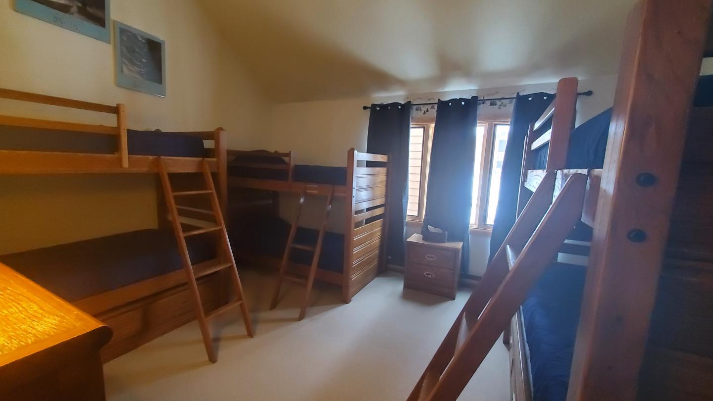 Bunk beds in a softly lit room with curtains and wooden furniture.