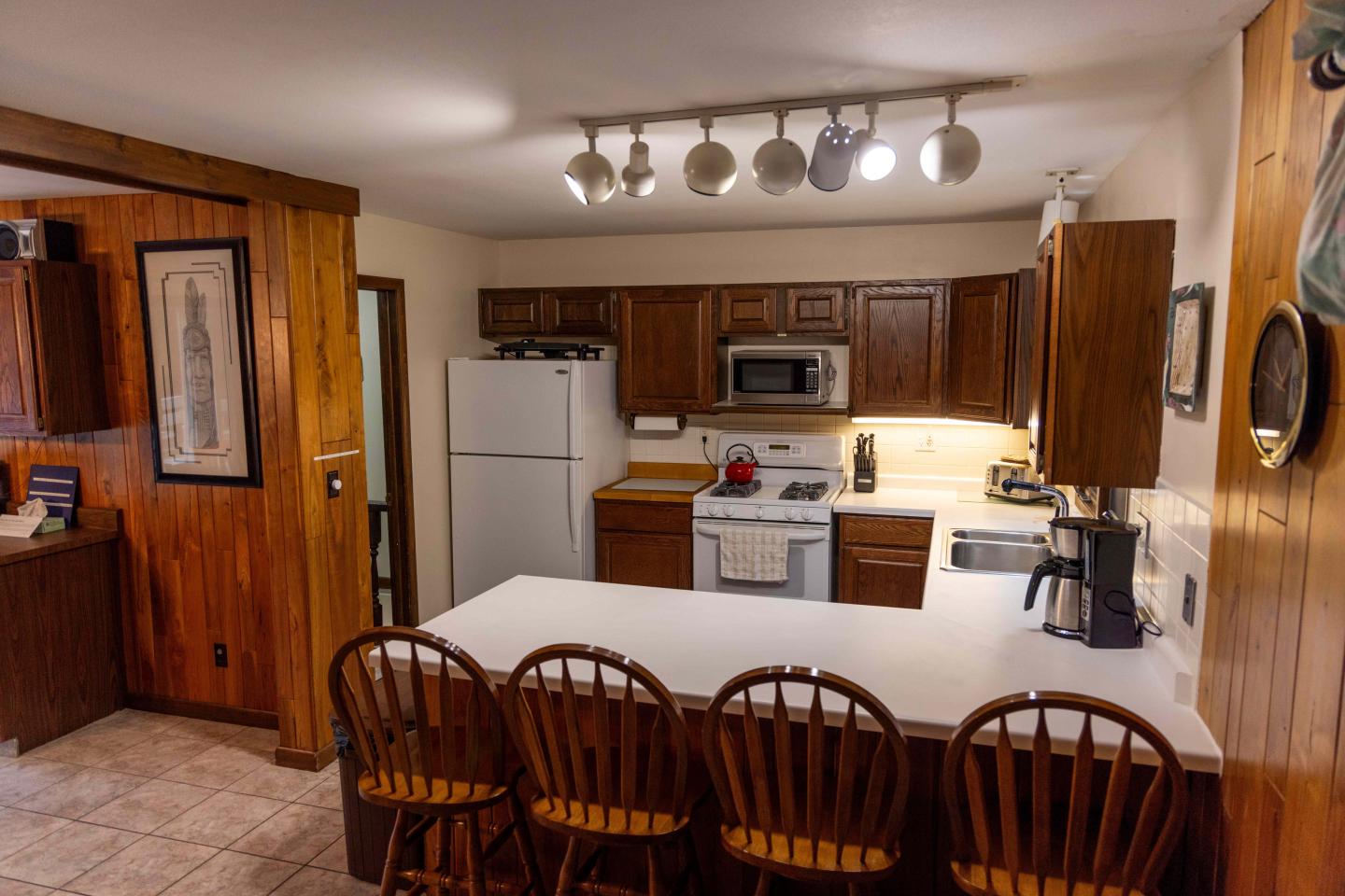 Cozy kitchen with wooden cabinets, white countertop, and barstools.
