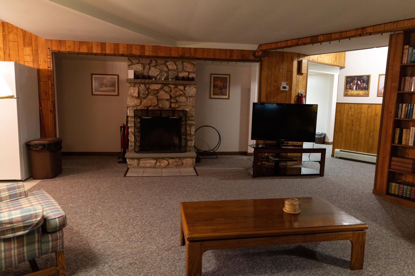 Cozy living room with a stone fireplace, TV, and wooden table.