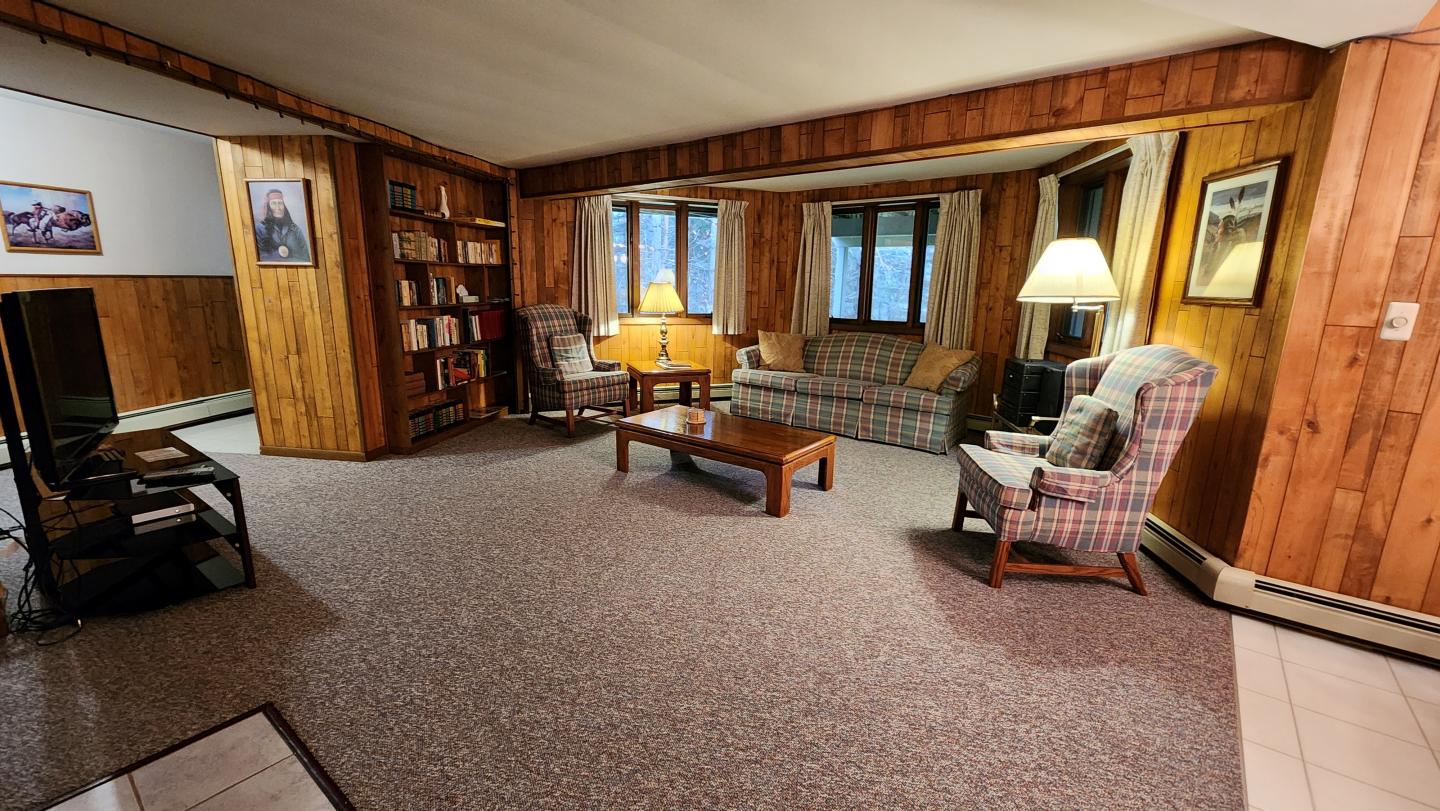 Cozy living room with wood paneling, sofas, a coffee table, and a lamp.