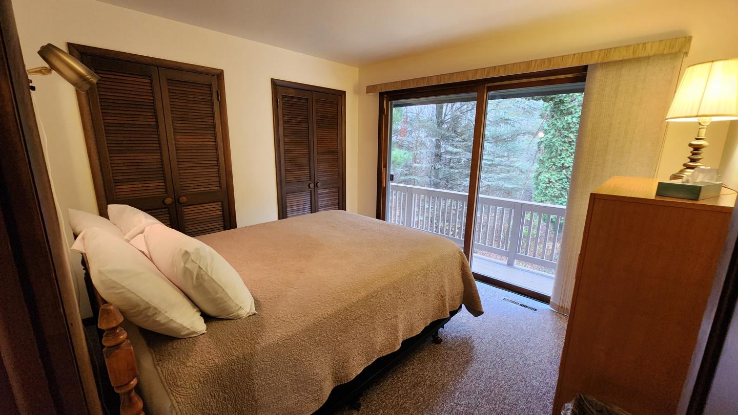 Cozy bedroom with a bed, lamp, and sliding glass door to a balcony.