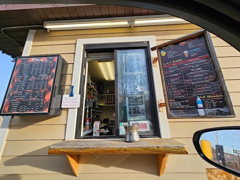 Drive-thru coffee stand with menu boards and a serving window.